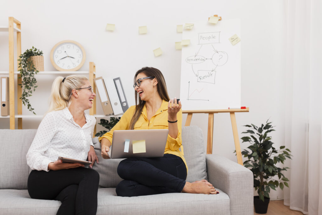women holding gadgets sitting sofa
